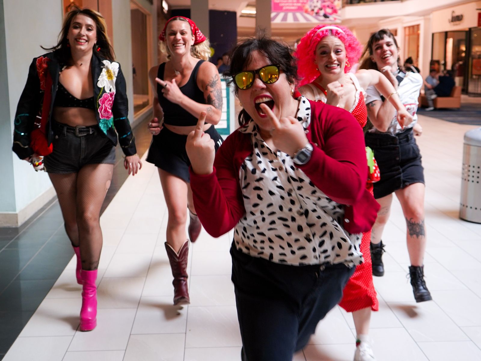 boo85, an all-women band, running and laughing through a shopping mall